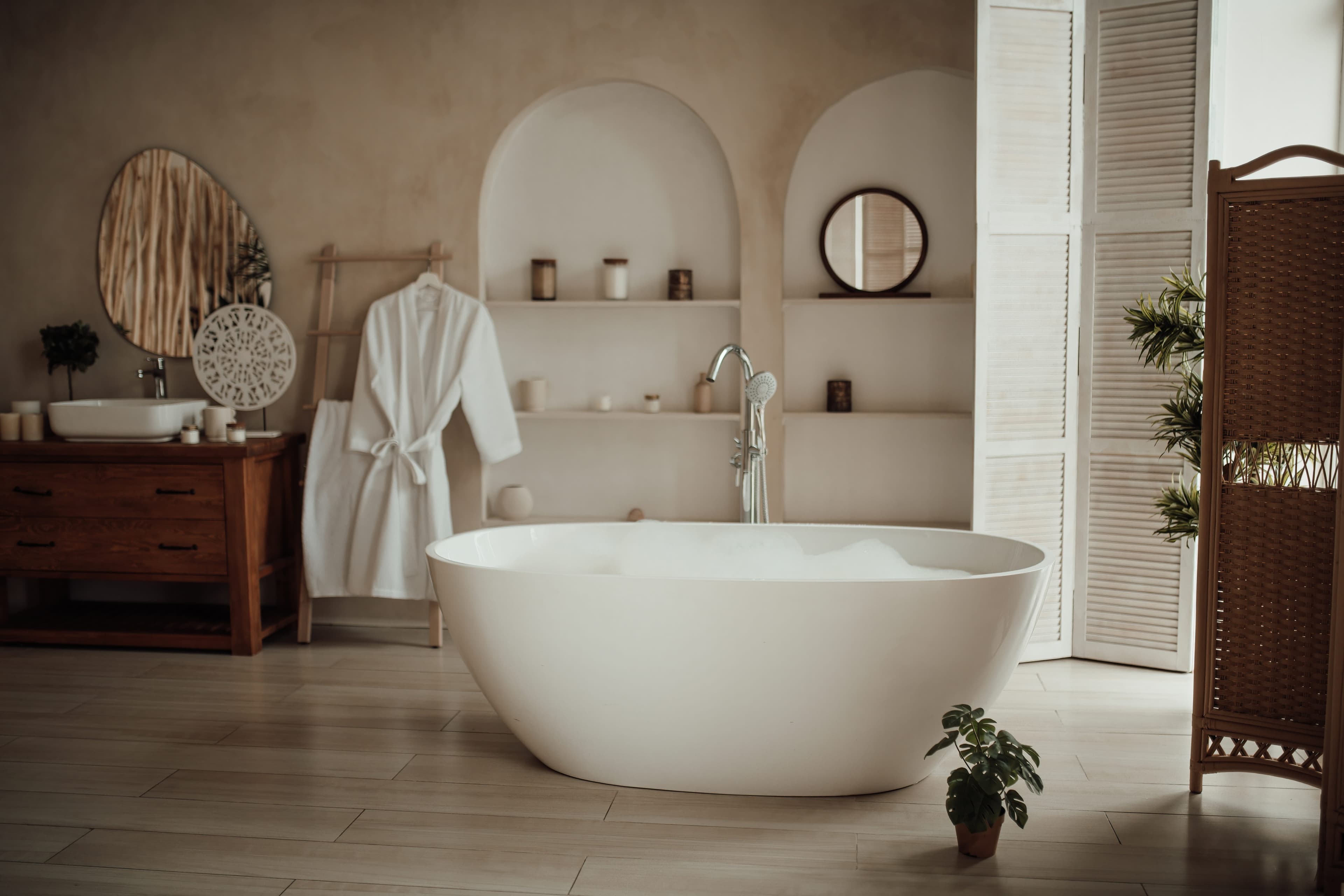 Warm spa-style bathroom with freestanding tub and arched niches