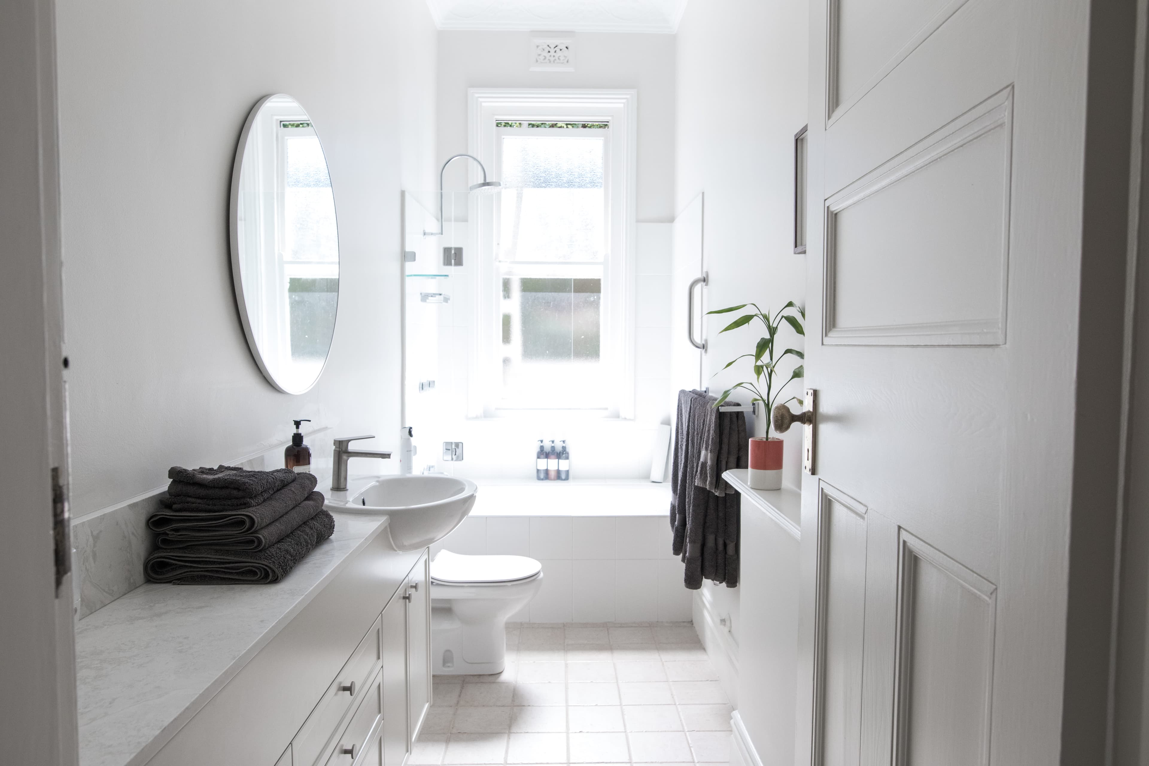 Bright white bathroom with oval mirror and full-width vanity